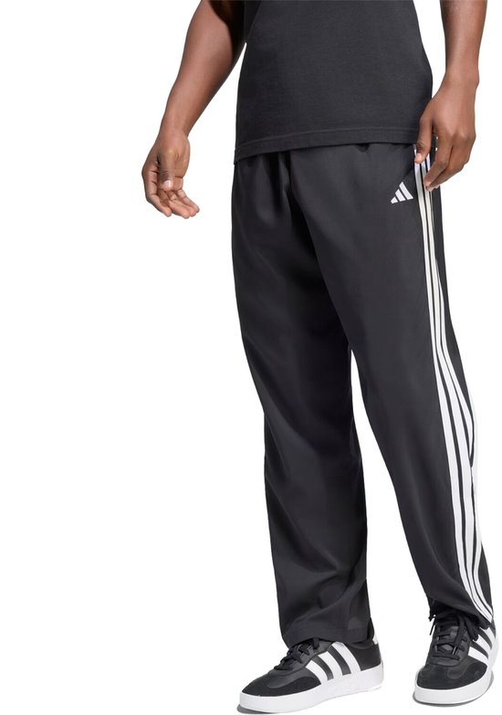 Man in zwarte sportbroek met witte Adidas strepen op de zijkant en Adidas logo op de heup.