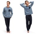 Man in lichtblauw pyjamapak met donkerblauwe broek en zak. Met handen achter hoofd.