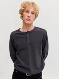 Model draagt een antracietgrijze henley-top met lange mouwen, structuur en knoopsluiting bij de hals.