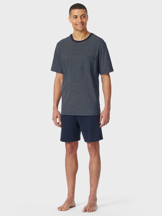 Model draagt een marineblauw T-shirt met stippenpatroon en bijpassende effen marineblauwe short.