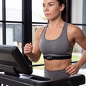 Vrouw met een VirtuFit hartslagmeter om haar borst, gekleed in sportkleding, traint op een loopband.