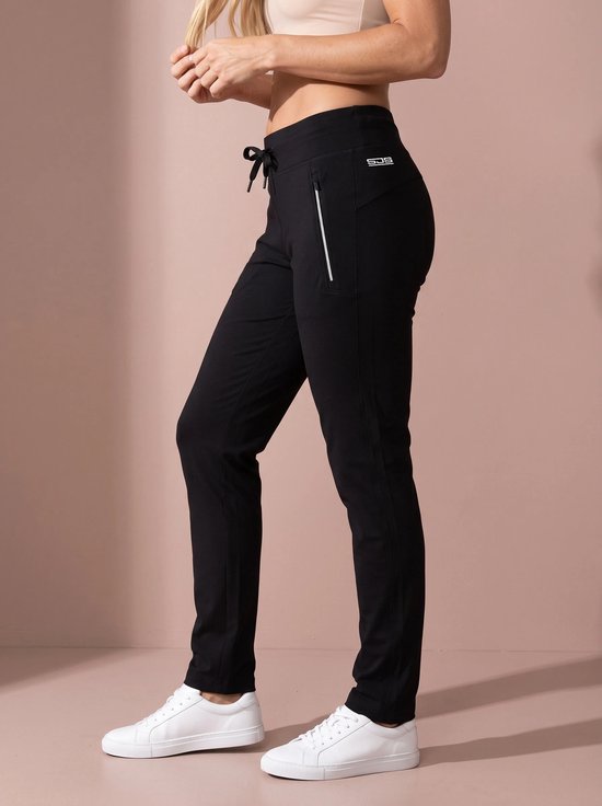 Zijaanzicht van een zwarte sportbroek met SJS-logo op de heup, trekkoord in de taille en witte sneakers.