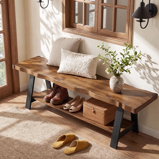 Houten bank met natuurlijke rand en metalen A-frame poten. Twee kussens, bruine laarzen, schoenen en mand op de plank.