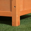 Detail van de houten poten van een bruin hondenhok op groen gras.