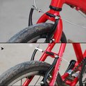 Close-up van een zwarte fietsrem op de voor- en achterkant van een rode fiets.