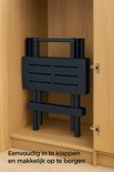 Donkerblauwe inklapbare tafel opgeborgen in een kast.
