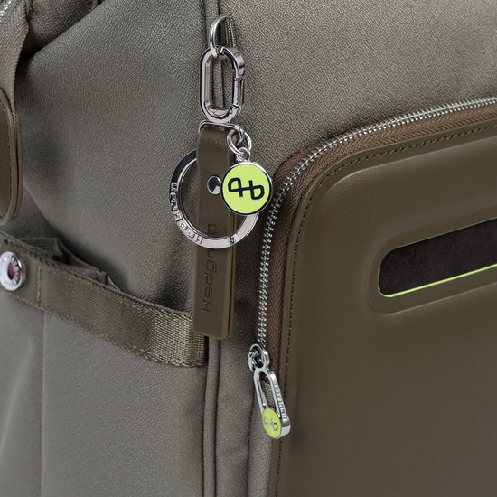 Close-up van een tas met een sleutelhanger met een geel logo en bruine leren details.