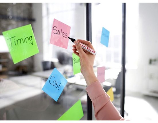 Hand schrijft 'Sales' op een roze post-it met een Edding 3000 marker.