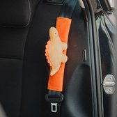 Oranje dinosaurus gordelhoes op een autogordel in een zwarte autostoel.