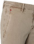 Detail van voorzak met rood label en stiksels op beige chino broek.