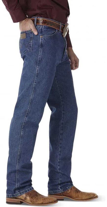 Man in een bordeaux overhemd, bruine riem en blauwe jeans, zijaanzicht.