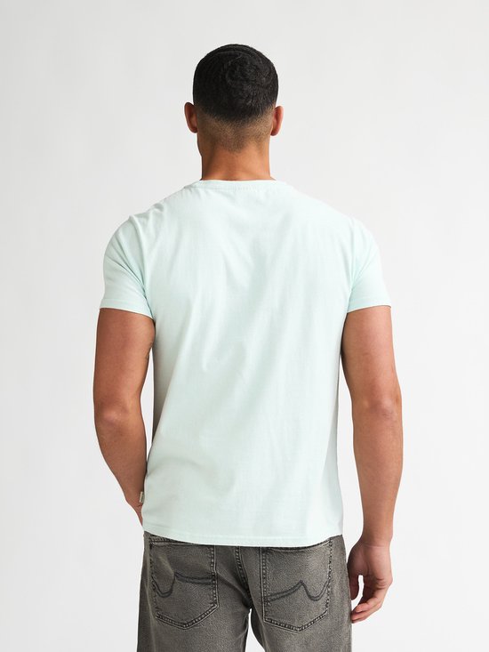 Man in lichtgroen T-shirt, rug zichtbaar, met label rechtsonder.