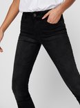 Model in zwarte skinny jeans, met de hand in de zak.