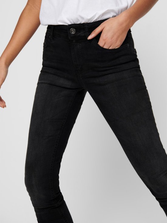 Model in zwarte skinny jeans, met de hand in de zak.