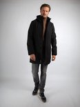 Man in zwarte jas, beige coltrui, grijze jeans, sneaker.