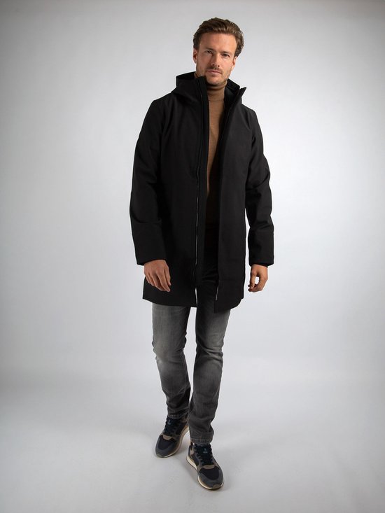 Man in zwarte jas, beige coltrui, grijze jeans, sneaker.