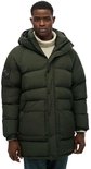 Een man draagt een lange, donkergroene, gewatteerde parka met capuchon, ritssluiting en knopen.