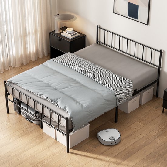 Cadre de lit en métal noir avec couette à rayures, draps gris et couverture à carreaux noir et blanc, avec boîtes de rangement sous le lit.