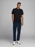 Zwarte polo met korte mouwen, gedragen door een man in een corduroy broek en sneakers. Volledige outfit.