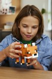 Un garçon en veste en jean regarde le renard LEGO Minecraft constructible qu'il tient.
