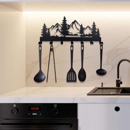 Zwart metalen sleutelhanger met bergen en bomen silhouet, hangt boven een aanrecht en is versierd met keukengerei.