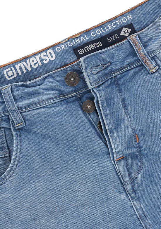 Close-up van de knoopsluiting en tailleband van een lichtblauwe denim short met oranje details.