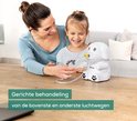 Moeder en dochter, die lachend naar elkaar kijken, terwijl het meisje de inhalator gebruikt. Witte hond inhalator ernaast.