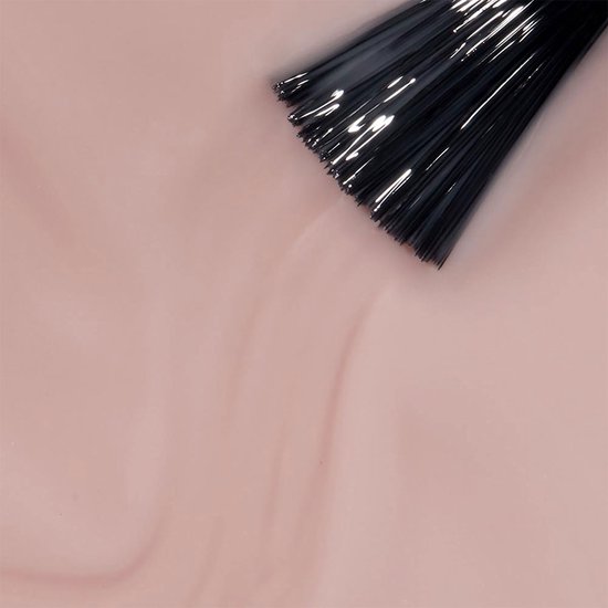 Close-up van een penseel dat nude nagellak aanbrengt op een glanzend oppervlak.