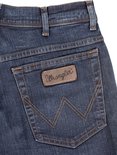 Close-up van de achterzak van een Wrangler jeans met stiksels in W-vorm en bruin label.