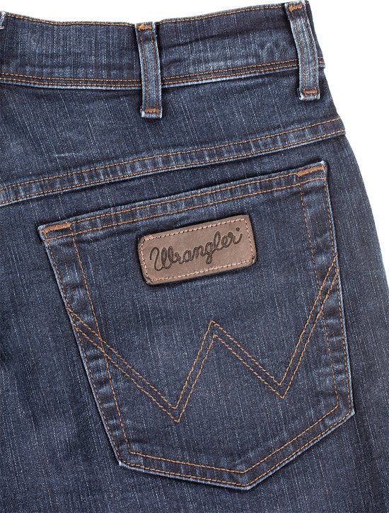 Close-up van de achterzak van een Wrangler jeans met stiksels in W-vorm en bruin label.