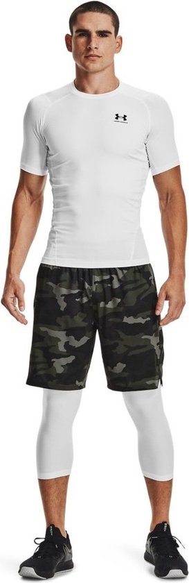 Man met wit, aansluitend sportshirt met korte mouwen, camouflage shorts en witte driekwart leggings.