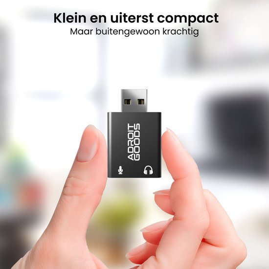 Hand die een kleine zwarte USB-geluidskaartadapter vasthoudt met microfoon- en hoofdtelefoonaansluitingen.