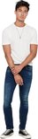 Man met wit gestreept T-shirt en donkerblauwe skinny jeans. Draagt zwarte sneakers.