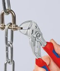 Hand houdt een Knipex tang met rood-blauwe handvatten vast om een metalen ketting te manipuleren.