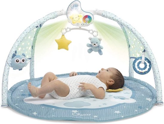 Babygym met boog, speelmat en baby. De mat is blauw met sterren en wolken. Er hangen speeltjes aan de boog, waaronder een beer en een ster.