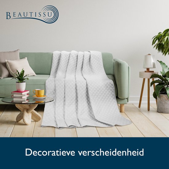 Witte sprei met ruitpatroon op een groene bank.