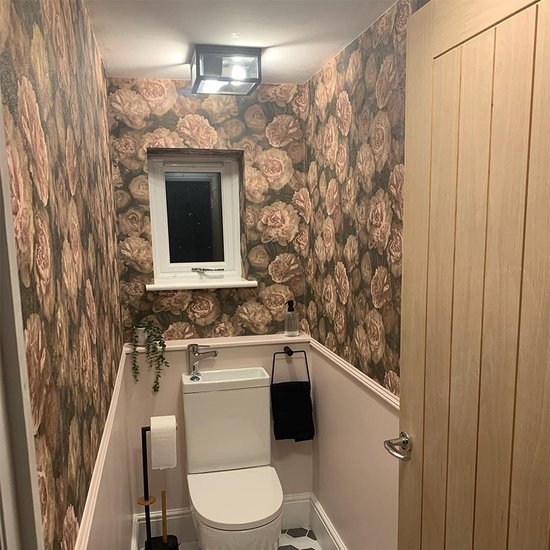 Zwarte vierkante plafondlamp met glas, gemonteerd aan een muur met bloemenbehang.