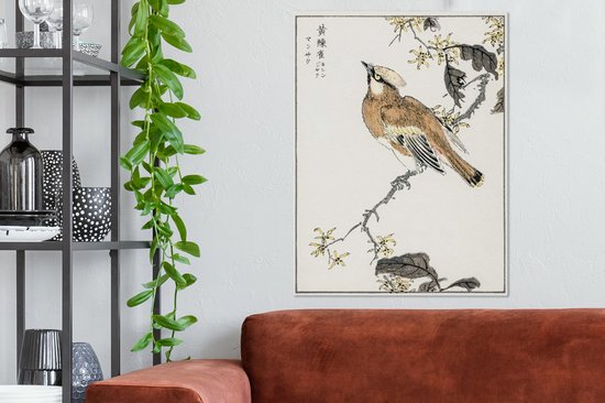 Une estampe japonaise d'un oiseau sur une branche aux fleurs jaunes, suspendue au-dessus d'un canapé brun rouille.