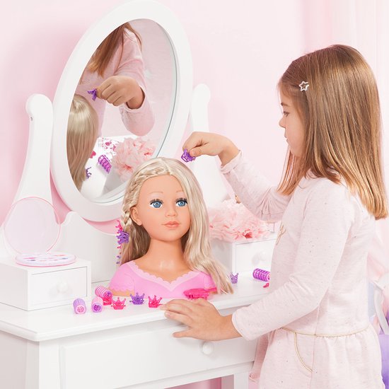 Meisje stylet de vlecht van een kaphoofd met blond haar aan een kaptafel.