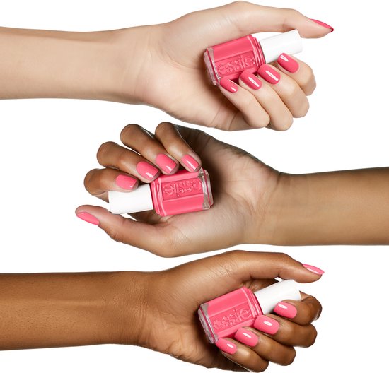 Drie handen met verschillende huidtinten houden elk een Essie nagellakflesje vast, met nagels gelakt in de koraalroze kleur 'cute as a button'.