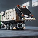 Achterkant van een LEGO vuilniswagen met witte container die omhoog wordt gehouden. Zwarte klep met oranje lichten.