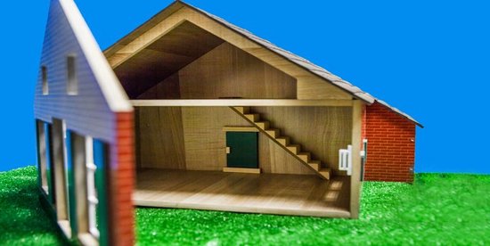 Open speelgoedboerderij met houten interieur, trap en rode bakstenen muur.