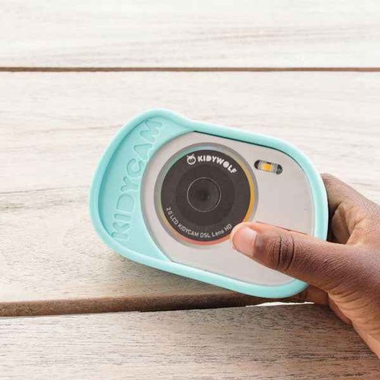 Een hand houdt een cyaan Kidycam vast. De camera heeft een beschermhoes met "KIDYCAM" erop.