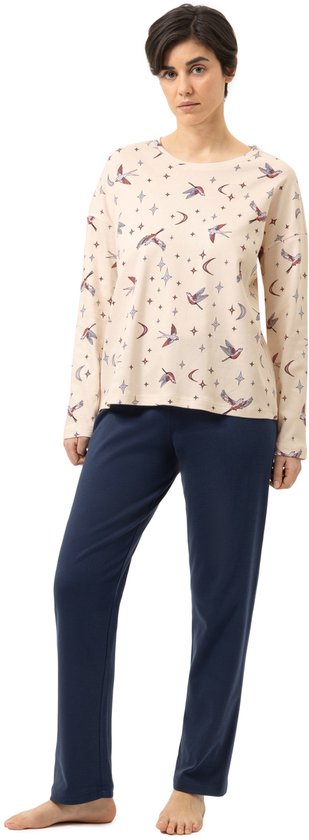 Model draagt lichtbeige pyjamashirt met lange mouwen en print van vogels, manen en sterren, met donkerblauwe pyjamabroek.