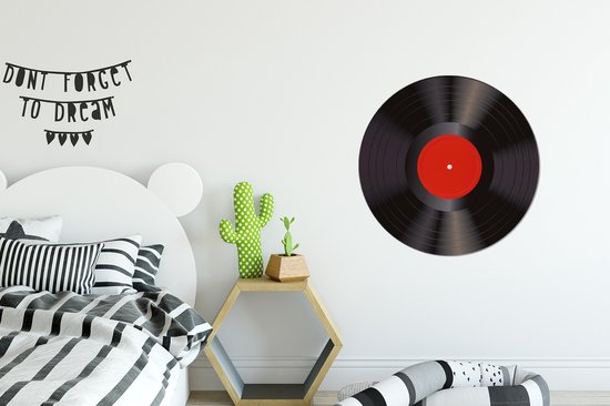 Zwarte vinyl LP met rood middellabel, hangend aan een muur boven een bed.