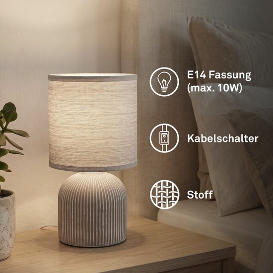 Lampe de table avec abat-jour en tissu et pied en céramique sur une table de chevet, avec icônes pour douille, câble et matériau.