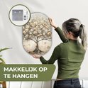 Vrouw hangt een ovaal kunstwerk van 3 mm dik kunststof met een beige, gouden en grijze boom op.