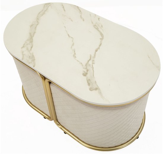 Ovale salontafel met marmerlook blad en gouden frame, met twee crèmekleurige, gewatteerde poefs eronder geschoven.