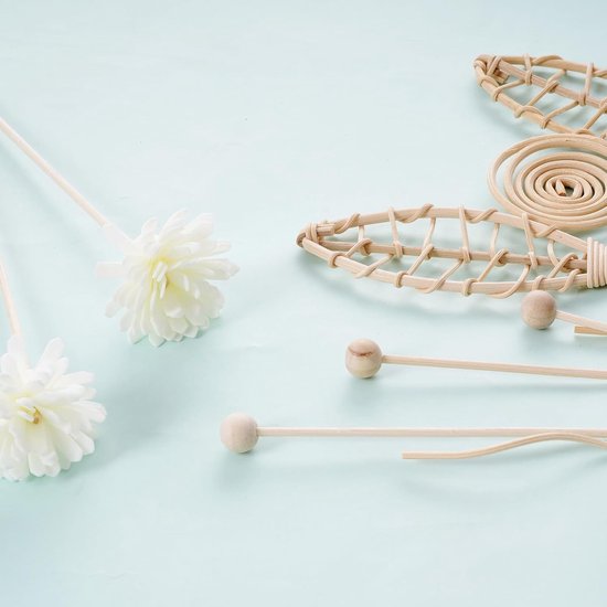Losse decoratieve geurstokjes: witte bloemen, gevlochten bladeren, spiralen en houten knikkers op stokjes.