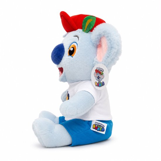 Zijaanzicht lichtblauwe pluche koala met rode pet, witte T-shirt en blauwe broek.